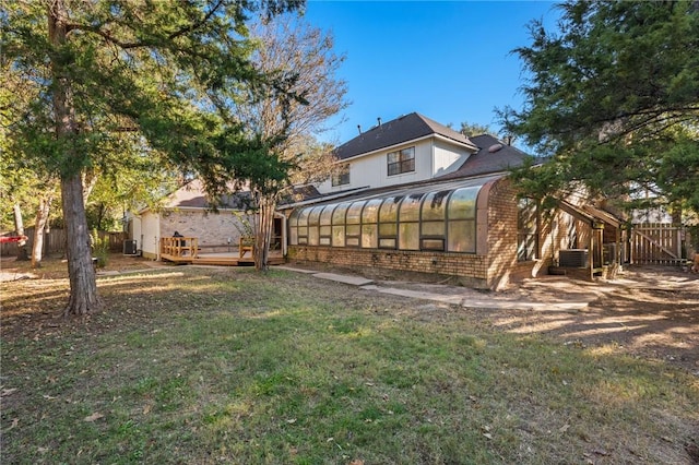 rear view of property with a yard, a wooden deck, and a sunroom