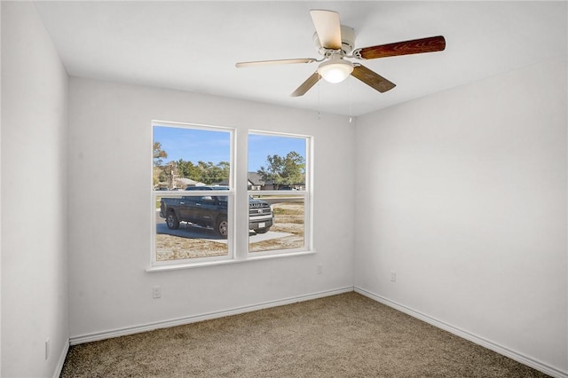 carpeted empty room featuring baseboards and a ceiling fan