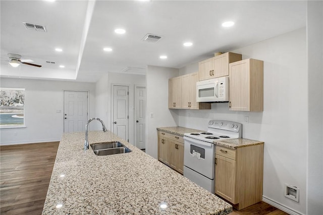 kitchen with light stone counters, white appliances, light brown cabinets, and a sink