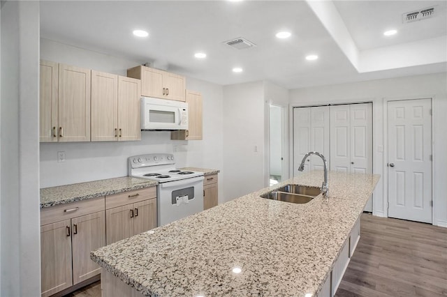 kitchen with an island with sink, white appliances, visible vents, and a sink