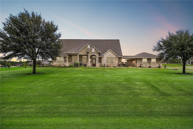 view of front of house with stone siding and a lawn