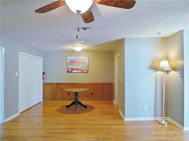 unfurnished dining area featuring ceiling fan, light hardwood / wood-style floors, and a textured ceiling