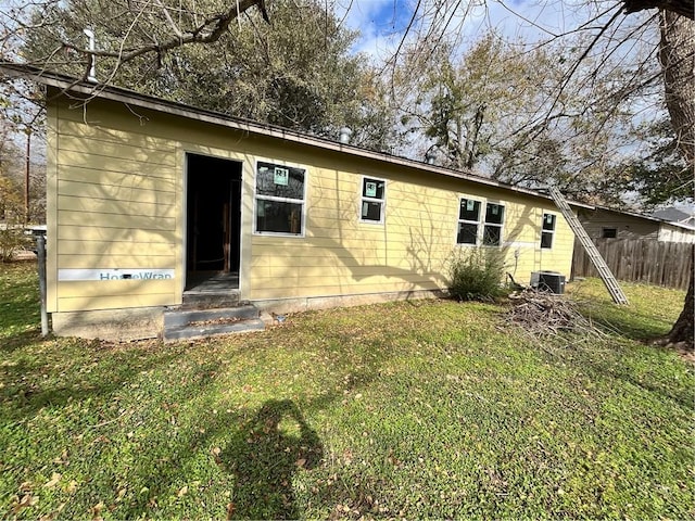 back of property featuring a lawn and central air condition unit