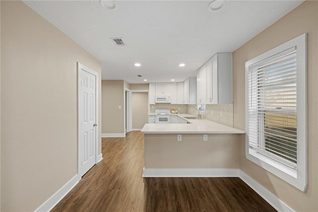 kitchen featuring white appliances, white cabinets, sink, decorative backsplash, and kitchen peninsula