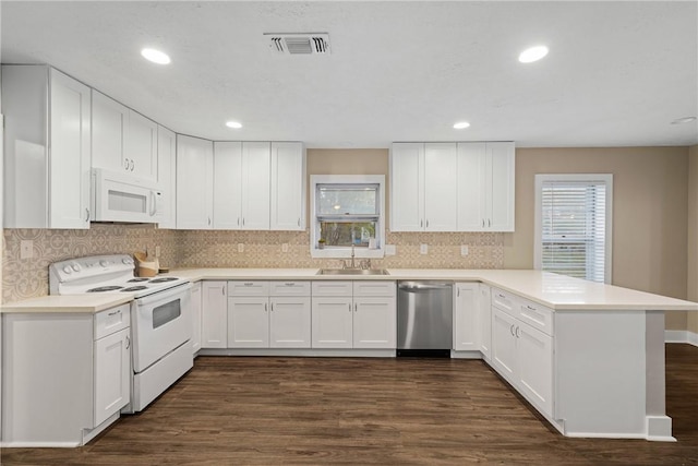 kitchen with white cabinetry, sink, dark hardwood / wood-style floors, kitchen peninsula, and white appliances