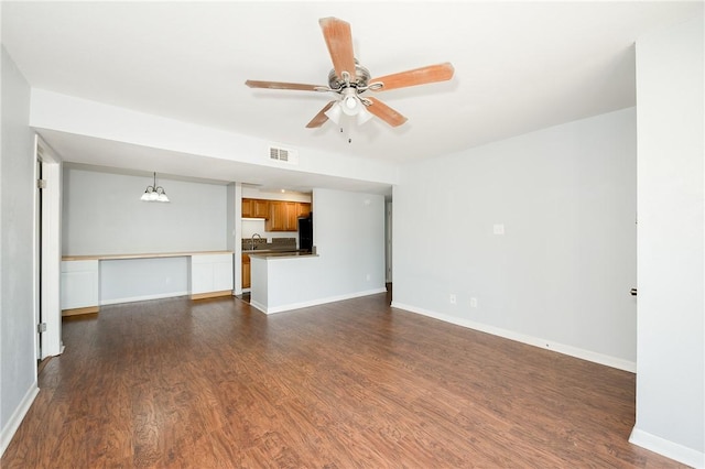 unfurnished living room featuring ceiling fan with notable chandelier, dark hardwood / wood-style flooring, and sink