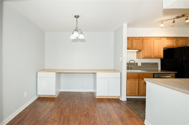 kitchen featuring black refrigerator, decorative light fixtures, sink, built in desk, and dark hardwood / wood-style floors