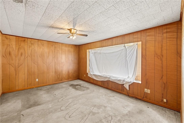 707 Norwood Ln, Hearne, TX 77859 - empty room featuring a ceiling fan, wooden walls, concrete floors, and baseboards