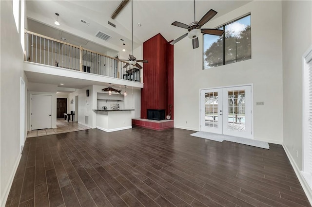 unfurnished living room with beamed ceiling, dark hardwood / wood-style floors, high vaulted ceiling, and french doors