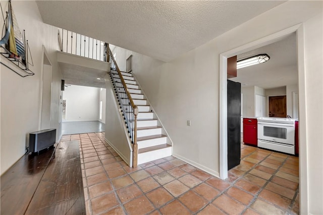 stairway with tile patterned flooring, baseboards, and a textured ceiling