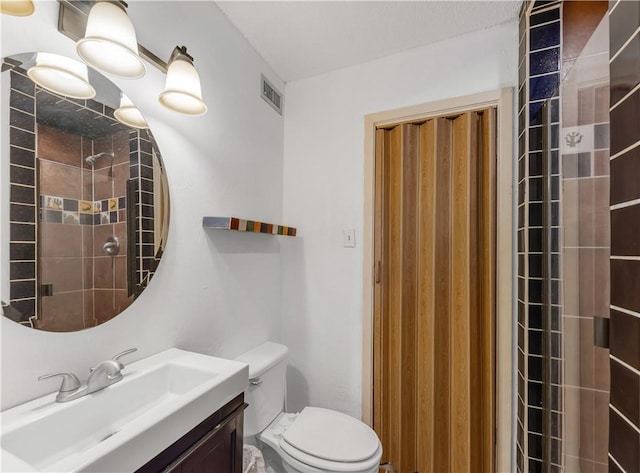 bathroom with vanity, toilet, and tiled shower