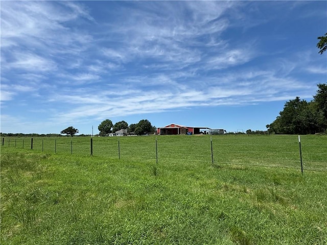 view of yard featuring a rural view, an outbuilding, and fence