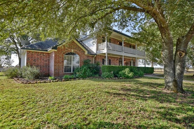 3151 Running River Ln, Washington, TX 77880 - traditional home featuring a balcony, brick siding, and a front lawn