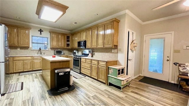 kitchen featuring appliances with stainless steel finishes, light wood-type flooring, ornamental molding, sink, and a kitchen island