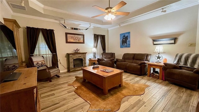 living room featuring a fireplace, light wood-type flooring, ceiling fan, and ornamental molding