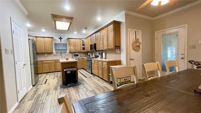 kitchen with ornamental molding, backsplash, appliances with stainless steel finishes, and light hardwood / wood-style flooring