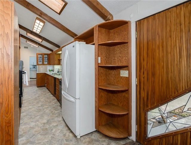 kitchen with washer / clothes dryer, lofted ceiling with skylight, and white refrigerator