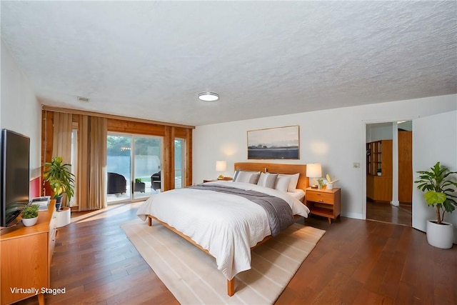 bedroom with dark wood-type flooring, access to exterior, and a textured ceiling