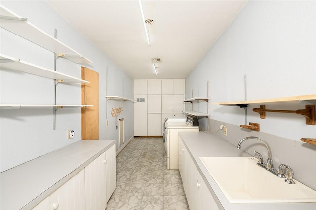 washroom with sink, washer / clothes dryer, and cabinets