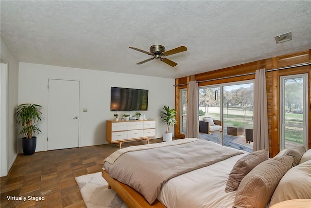 bedroom featuring ceiling fan, dark parquet flooring, access to exterior, and a textured ceiling