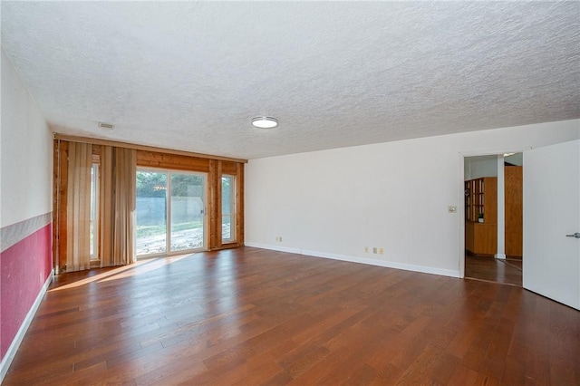 empty room with dark wood-type flooring and a textured ceiling