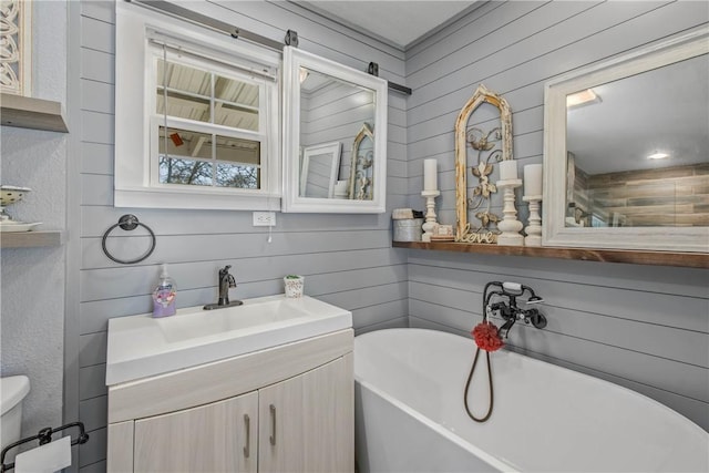 bathroom featuring a tub to relax in, vanity, and toilet