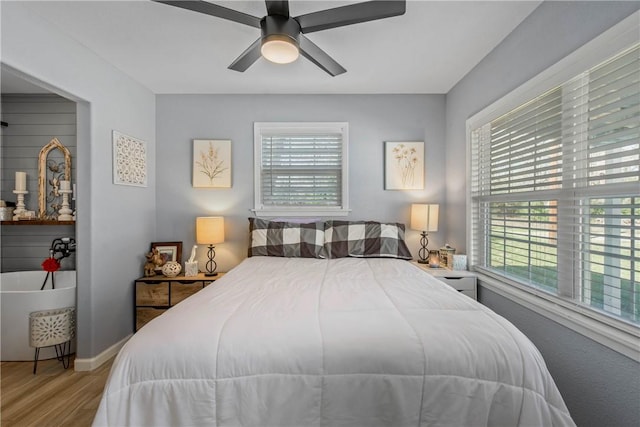 bedroom with ceiling fan, multiple windows, and hardwood / wood-style floors