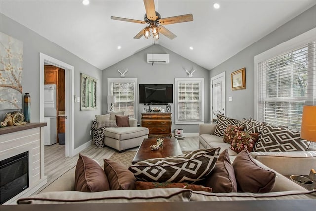 living room featuring vaulted ceiling, stacked washer and clothes dryer, light hardwood / wood-style flooring, a wall unit AC, and ceiling fan