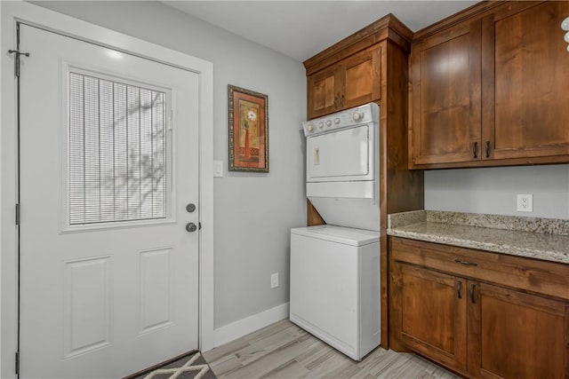 laundry room featuring cabinets and stacked washer and dryer