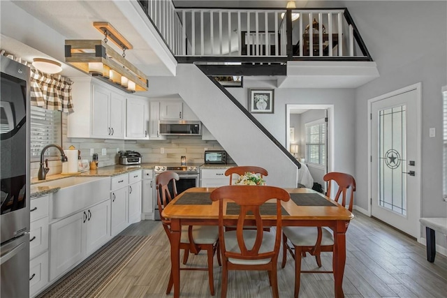 dining area with sink, hardwood / wood-style floors, and a towering ceiling