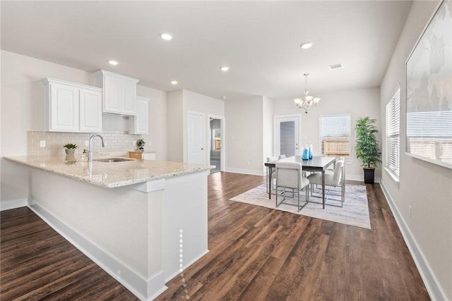 kitchen with kitchen peninsula, sink, pendant lighting, a notable chandelier, and white cabinets