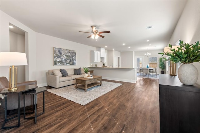 living room featuring dark wood-type flooring and ceiling fan with notable chandelier