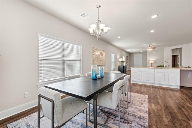 dining space with ceiling fan with notable chandelier and dark hardwood / wood-style floors