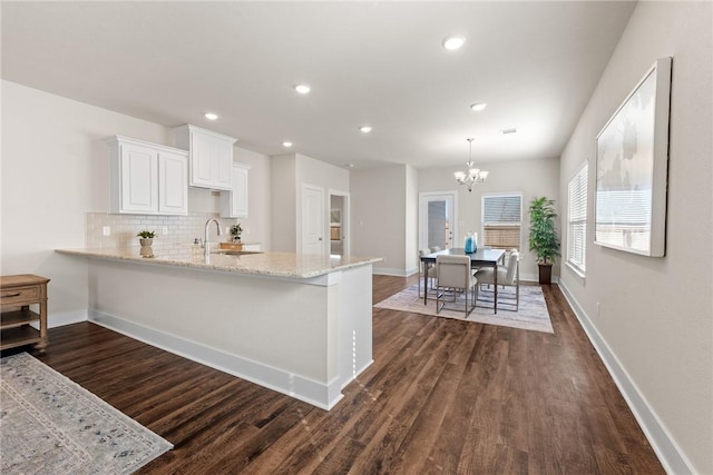 kitchen featuring white cabinets, decorative backsplash, decorative light fixtures, kitchen peninsula, and a chandelier