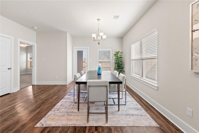 dining space with dark wood-type flooring and a notable chandelier