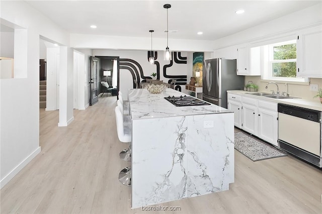 kitchen featuring pendant lighting, white dishwasher, white cabinets, a kitchen island, and stainless steel refrigerator