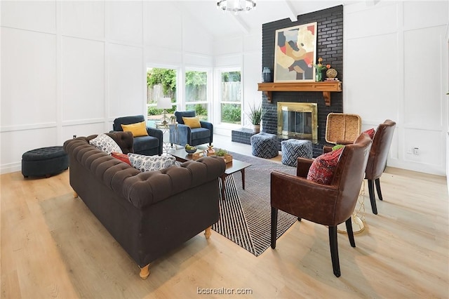 living room featuring a brick fireplace, vaulted ceiling, and light hardwood / wood-style flooring