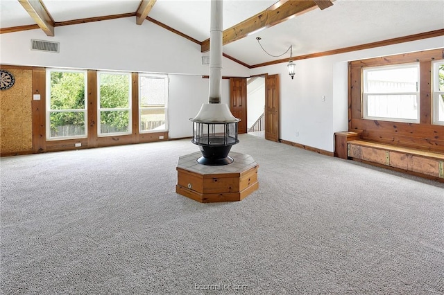 unfurnished living room featuring carpet flooring, a wood stove, beamed ceiling, and high vaulted ceiling