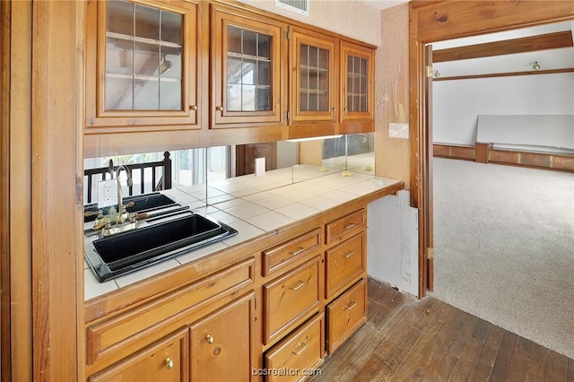 kitchen featuring tile counters, dark wood-type flooring, and sink