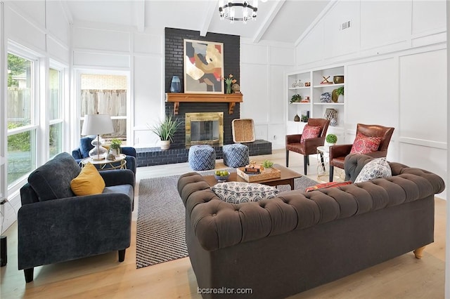 living room with beam ceiling, high vaulted ceiling, light hardwood / wood-style flooring, a notable chandelier, and a fireplace