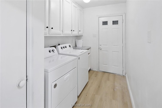 washroom featuring washer and clothes dryer, light hardwood / wood-style flooring, and cabinets