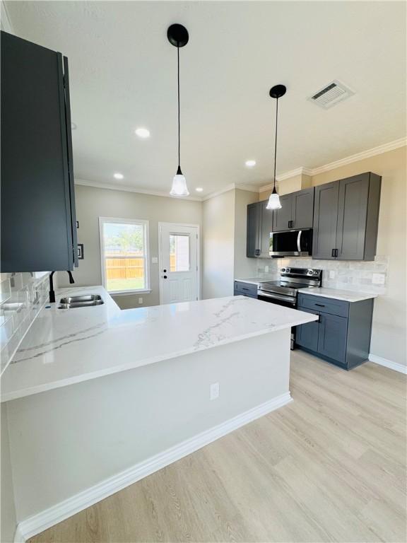 kitchen featuring sink, stainless steel appliances, light hardwood / wood-style flooring, kitchen peninsula, and pendant lighting