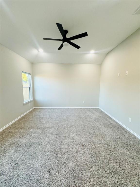 carpeted spare room with vaulted ceiling and ceiling fan