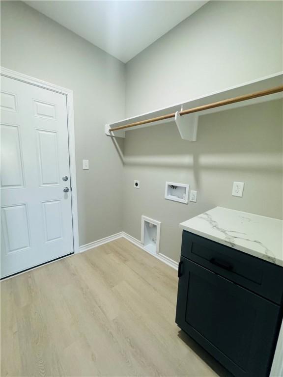 clothes washing area featuring electric dryer hookup, cabinets, hookup for a washing machine, and light hardwood / wood-style flooring