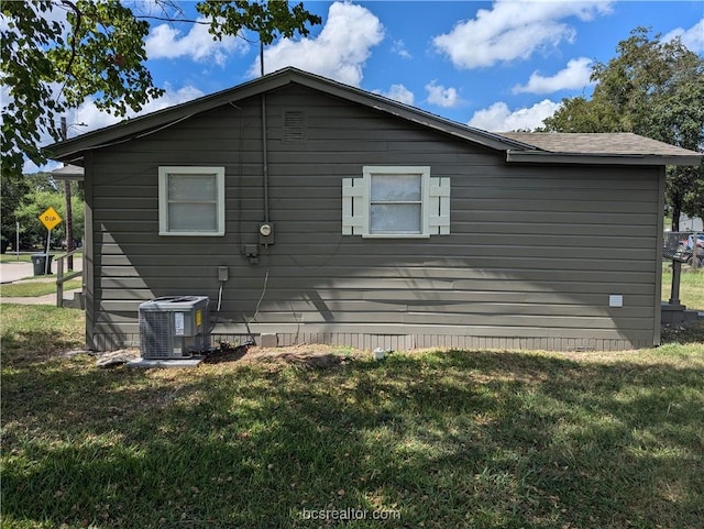 view of side of property with a lawn and cooling unit