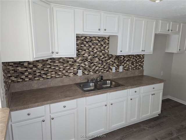 kitchen with backsplash, dark hardwood / wood-style flooring, white cabinetry, and sink