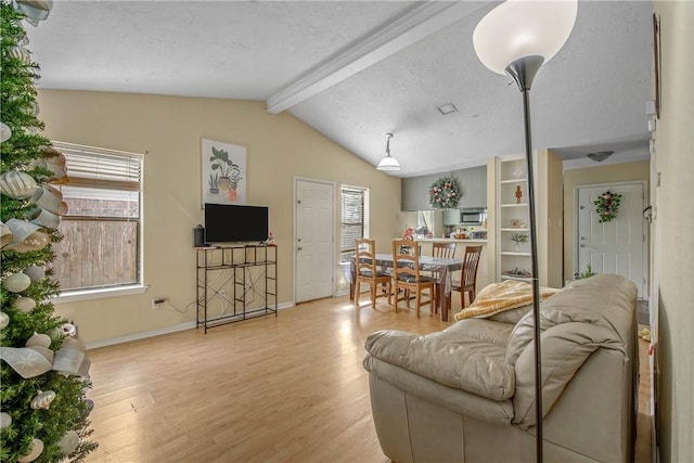 living room with light hardwood / wood-style flooring, lofted ceiling with beams, and a textured ceiling