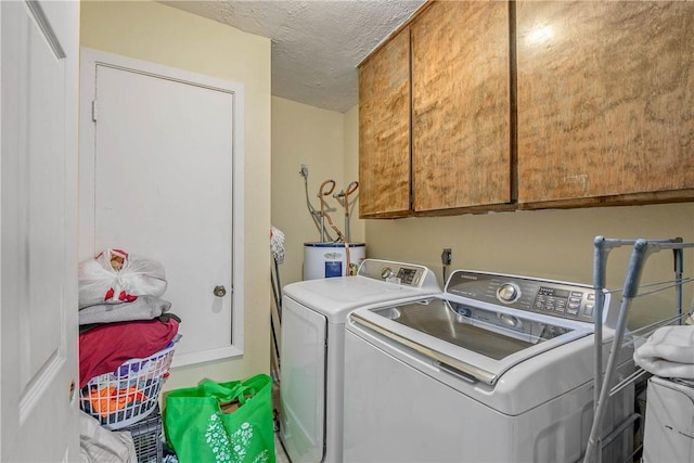 washroom with washer and dryer, a textured ceiling, electric water heater, and cabinets