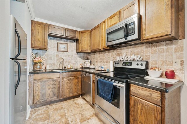 kitchen featuring appliances with stainless steel finishes, tasteful backsplash, crown molding, and sink