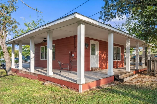 rear view of property featuring ceiling fan, a porch, and a yard